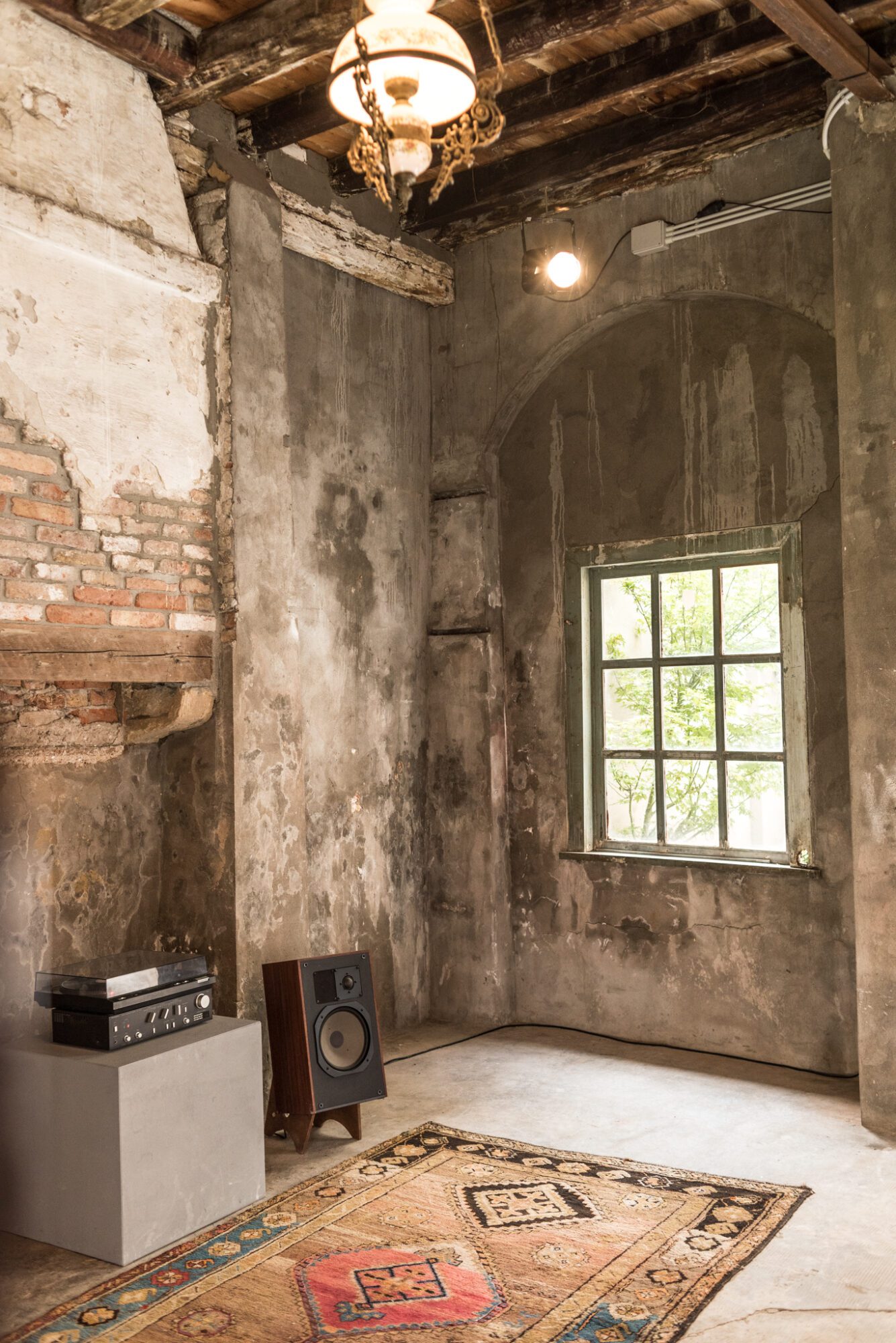 An installation view of Andrius Arutiunian piece with two speakers, a vinyl player, and carpets at Venice Biennale